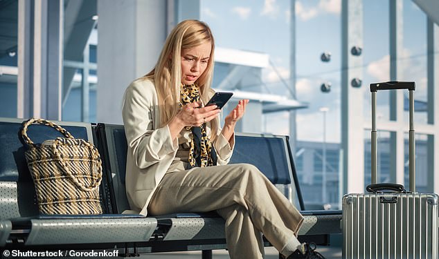 Woman looking at her phone in anger in an airport